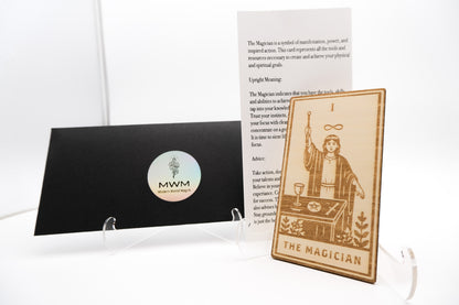 A tarot card set featuring 'The Magician' card displayed on a clear acrylic stand, next to a black card holder with a circular 'MWM Tarot Cards' logo, and an instruction card on a white background.