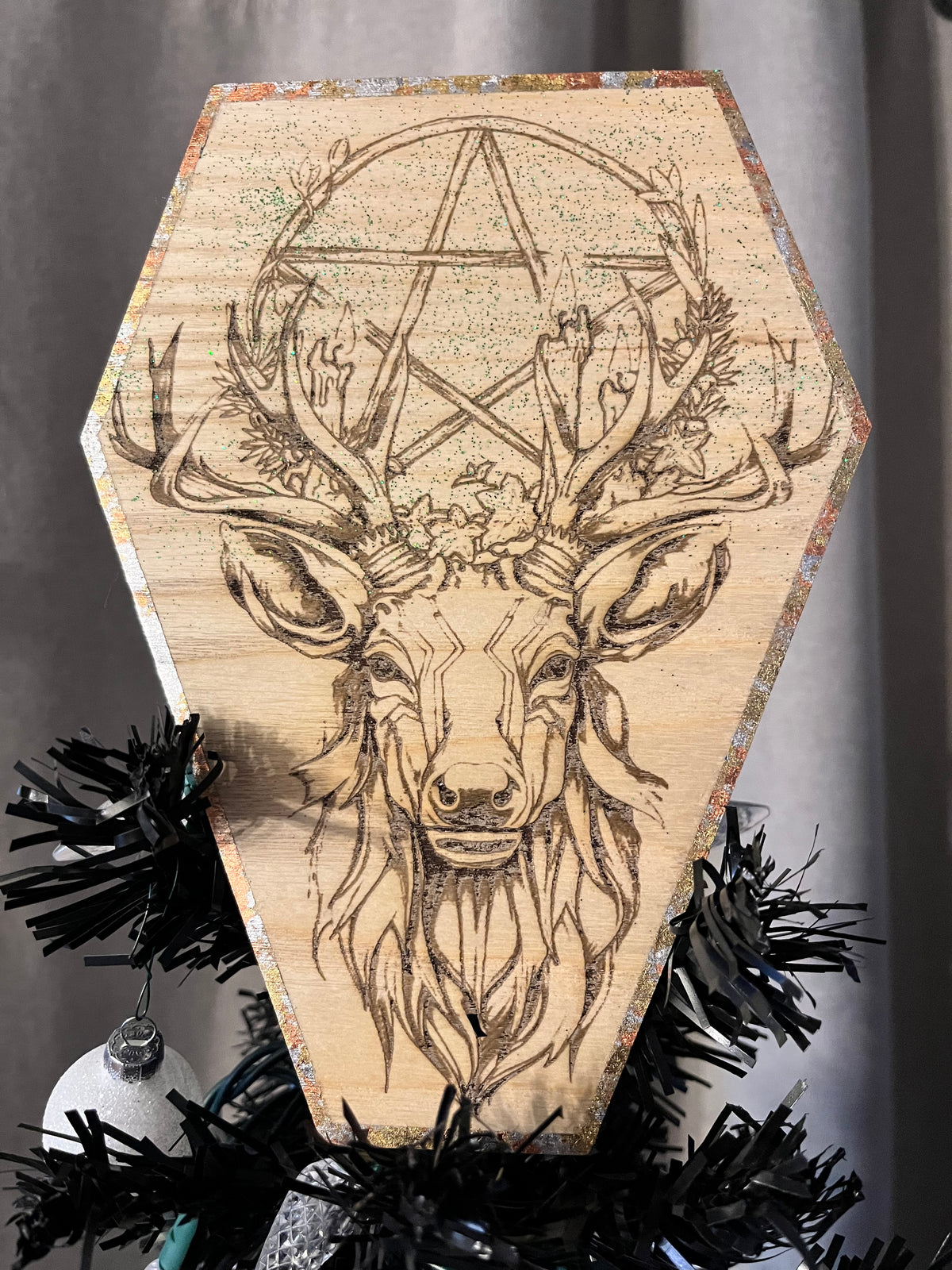 A decorative tree topper featuring an engraved image of an elk's head with antlers, surrounded by a gold and silver leafed border and green glitter.