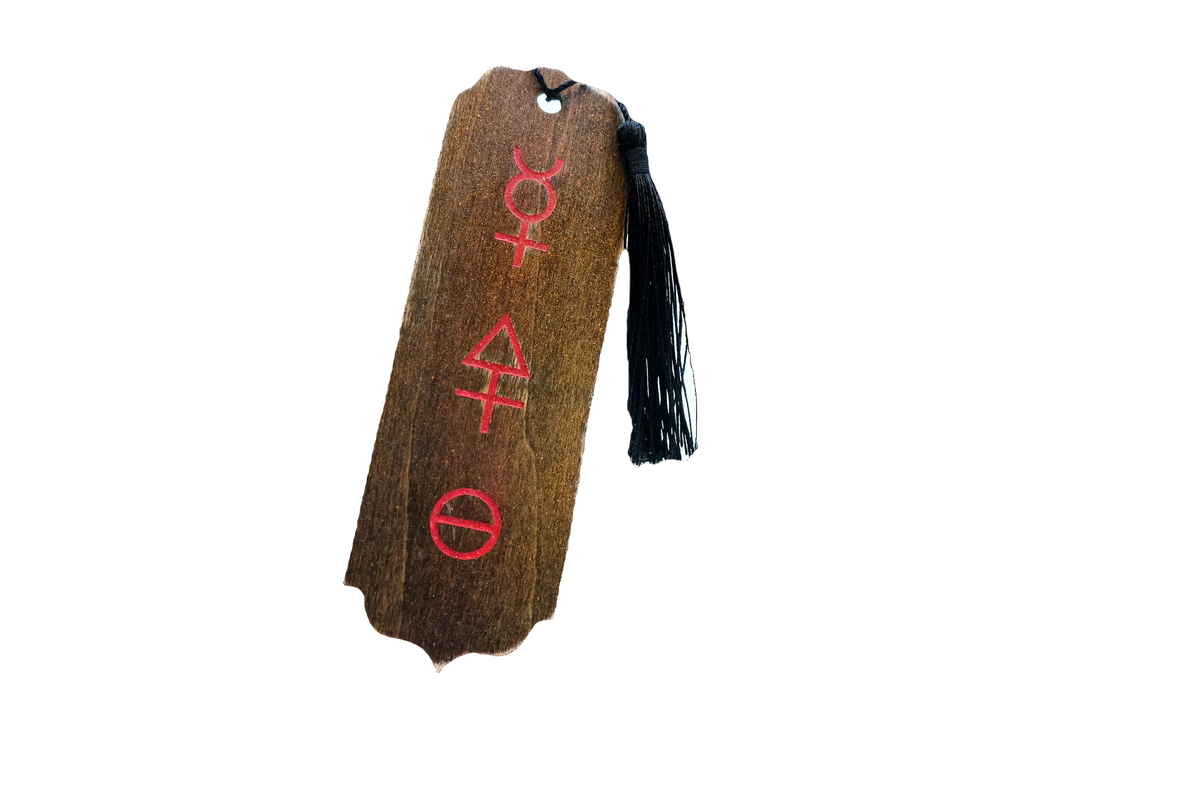 A rectangular wooden bookmark with a dark brown wood grain texture, featuring three red Tria Prima alchemical symbols vertically aligned. It has a small hole at the top and is finished with a black tassel hanging from the right side.
