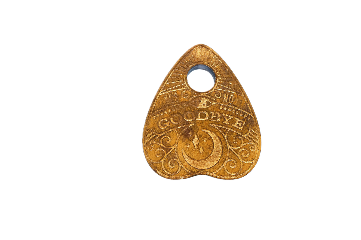 A hand-engraved wood planchette for talking-board work - sunburst crown, GOODBYE banner, open viewing window.