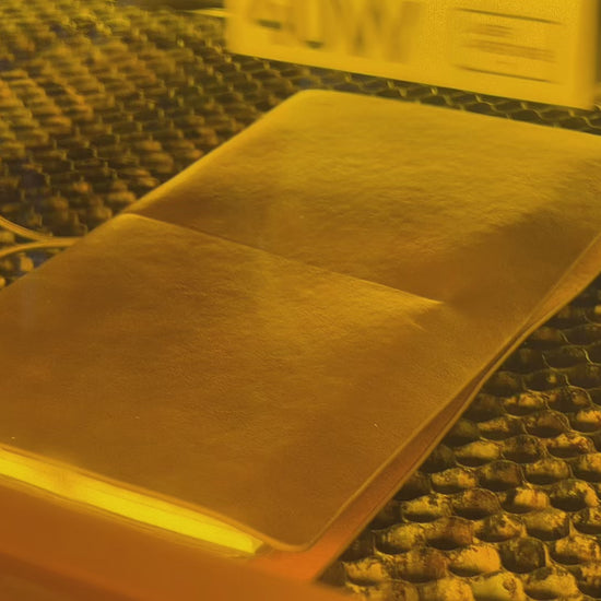 Laser engraver in process of engraving druidry symbols on a brown leather notebook.
