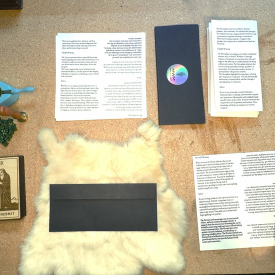 Man explaining the idea behind the Blind Tarot and packaging the wood cards into black envelopes and sealing with green wax.