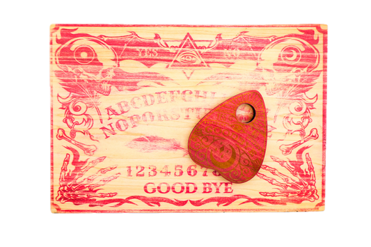 A carved wooden Ouija board with red-painted details and a matching wooden planchette resting on top.
