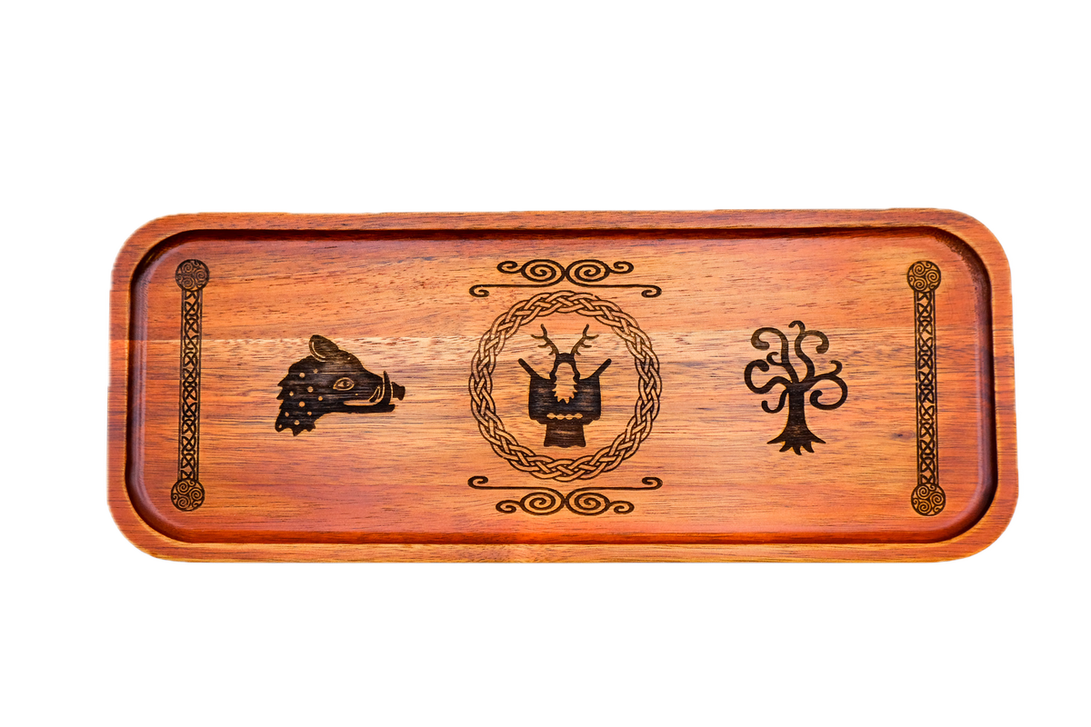 A rectangular wooden serving tray with a warm reddish-brown finish, featuring dark engraved symbols: a boar's head on the left, Cernunnos medallion, tree of life on the right, flanked by knotted pillar borders.